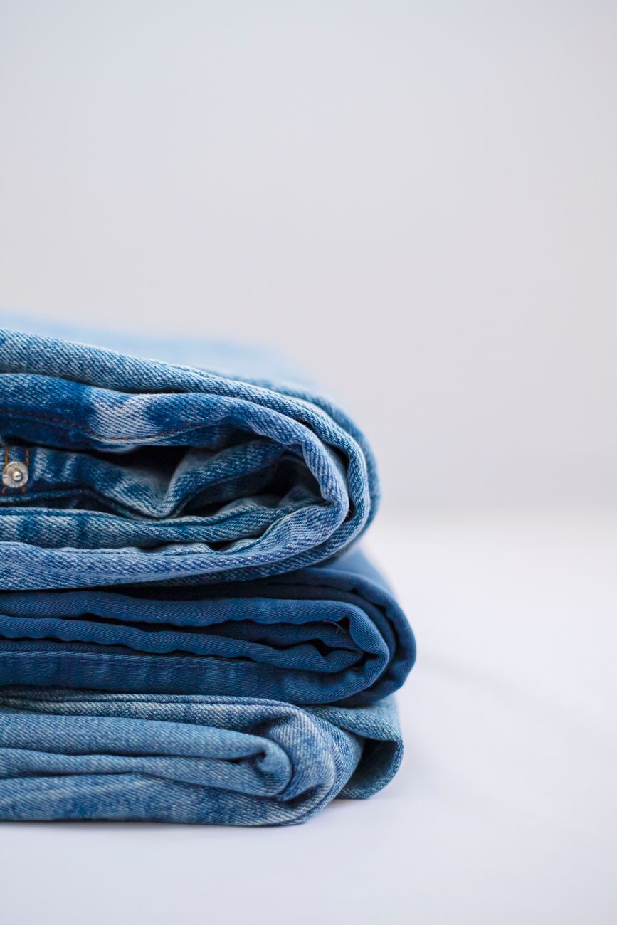 Pila prolija de jeans azules doblados sobre fondo liso